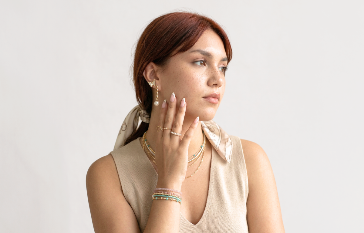 Woman wearing gold jewelry on a plain background
